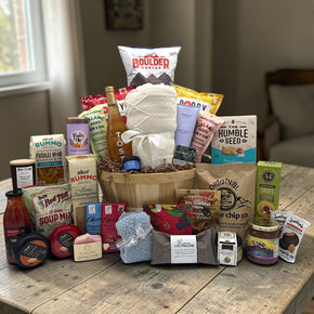 half bushel basket filled with a variety of snacks and spa items, pasta, sauce, popcorn, chips, caramels, and more