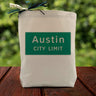Green Austin City Limit Sign on canvas tote bag sitting on a wood table with blurred green background.