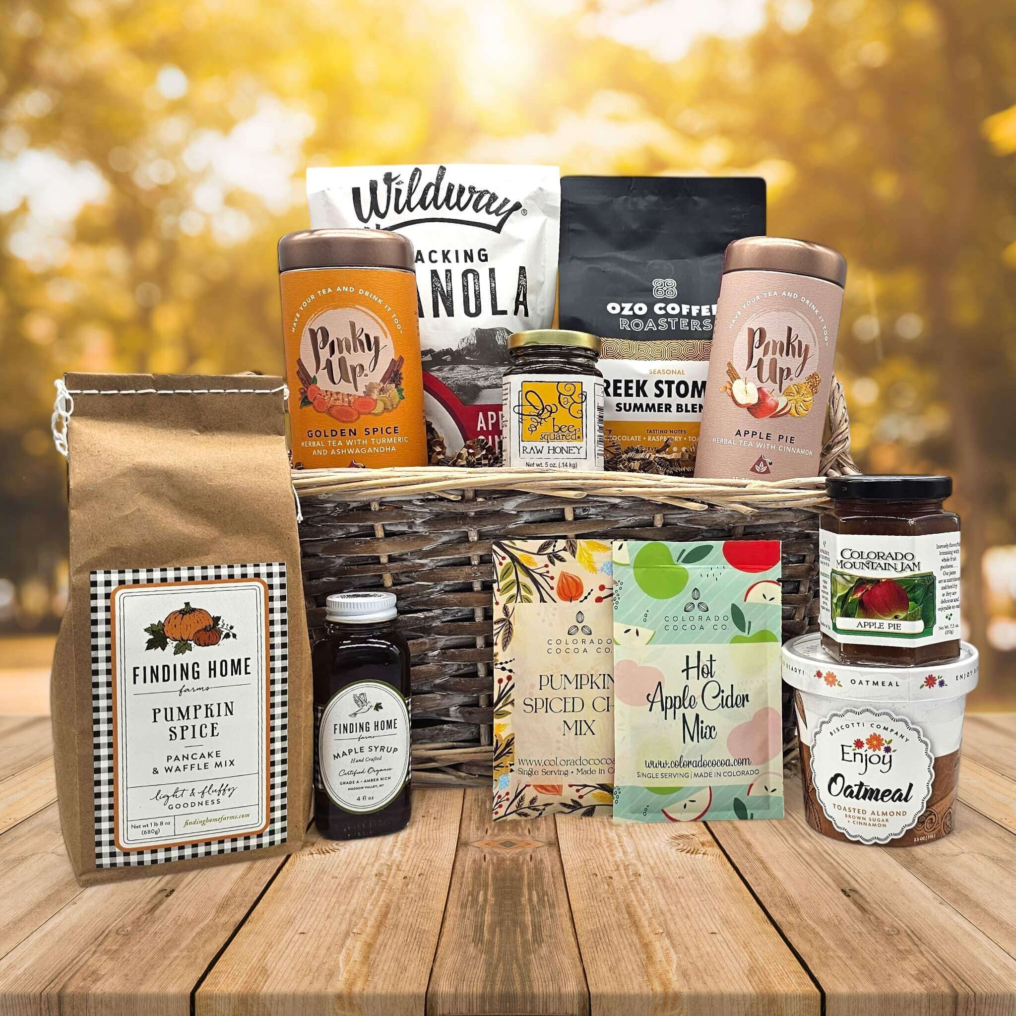 wicker basket filled with granola, coffee, teas, honey, pancake mix and syrup, jam and oatmeal