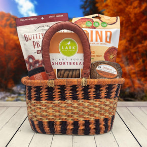 handwoven basket with toffee pretzels, fruit chips, honey, cookies and bread sitting on a table