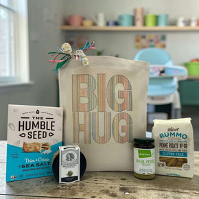 Striped "Big Hug" design on tote bag with crackers, bruschetta, pesto and pasta sitting on a table