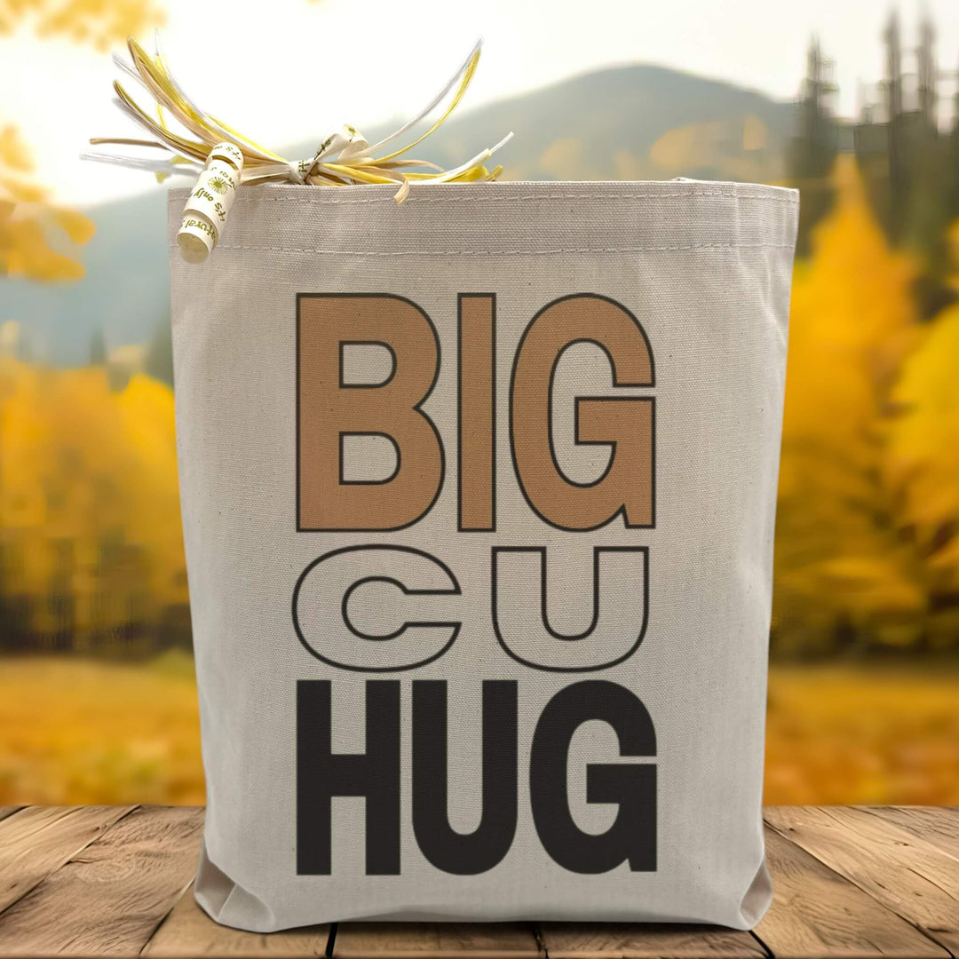 A big cu hug text beige and black colors  on a canvas tote bag placed on a wood table with woodsy background. 