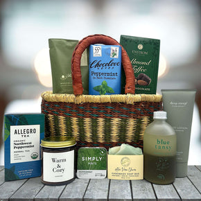 handwoven basket with bath salts, chocolate bar, almond toffee, tea, a large candle, mints, soap, bubble bath and lotion
