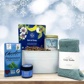 small tin tub with tea, a large candle, honey, chocolate bar, and socks all themed in the color blue