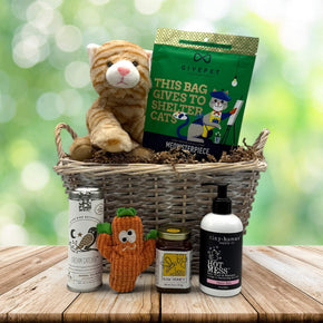 wicker basket with a stuffed cat, cat treats and toy, baby shampoo, and tea with honey