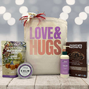 Love and hugs printed on tote bag with caramels, candle, lotion and cookies sitting on a table