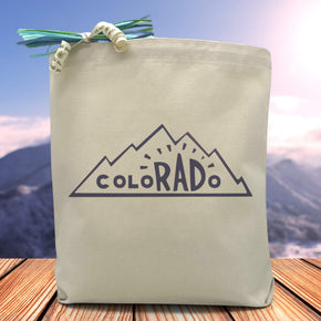 A blue text saying colorado with the r a d being larger and bolder than the surrounding letters all placed in the mountains printed on a canvas tote bag.