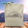 A blue text saying colorado with the r a d being larger and bolder than the surrounding letters all placed in the mountains printed on a canvas tote bag.