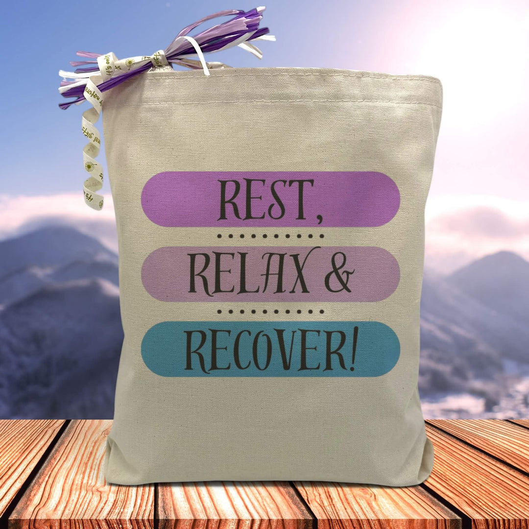 a black text saying rest, relax and recover with each of the words placed in a different color bar being purple light purple and blue printed on a canvas tote bag, 