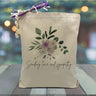  purple flowers with eucalyptus and green leaves surrounding it with a black text saying sending love and sympathy underneath printed on a canvas tote bag.