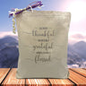  a grey stacked text saying so very thankful, incredibly grateful, unbelievably blessed printed on a canvas tote bag set on a wooden table with a mountain filled background,
