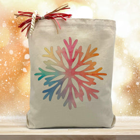 colorful snowflake printed on a canvas tote bag sitting on a table with a gold background