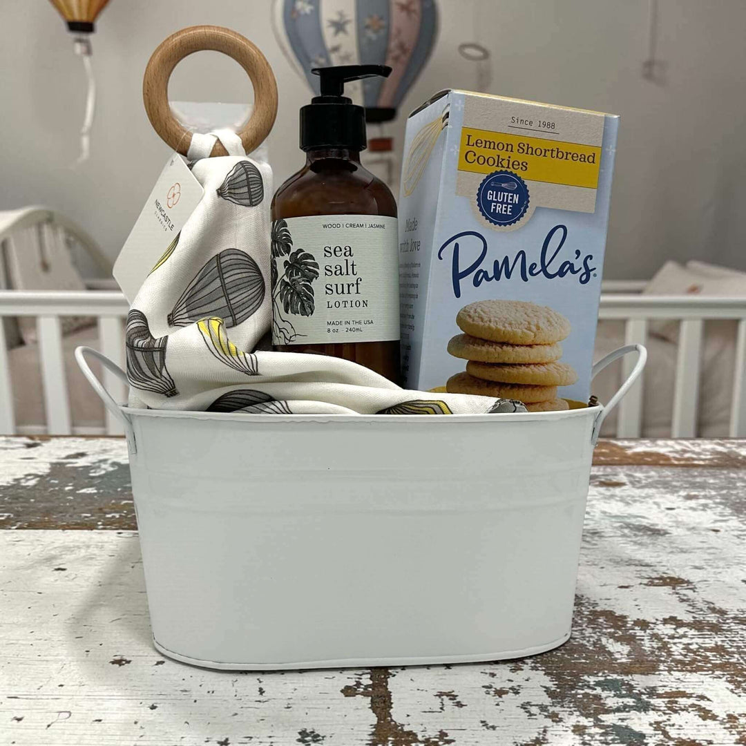 baby teether, lotion and lemon cookies inside of a small tin tub sitting on a table with a nursey background