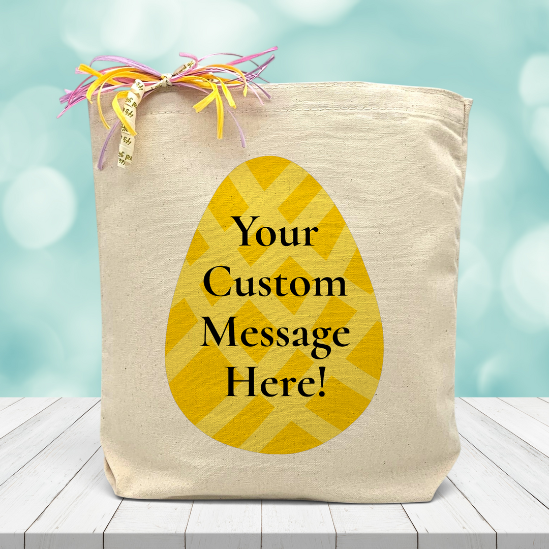 a yellow easter egg with the chance to place a custom message in the middle printed on a canvas tote bag set on a wooden table.