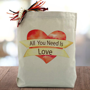 all you need is love printed on a red heart on a canvas tote bag