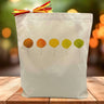 5 fall leaves in red, orange, yellow and green printed on a canvas tote bag sitting on a tbale with a blurred background