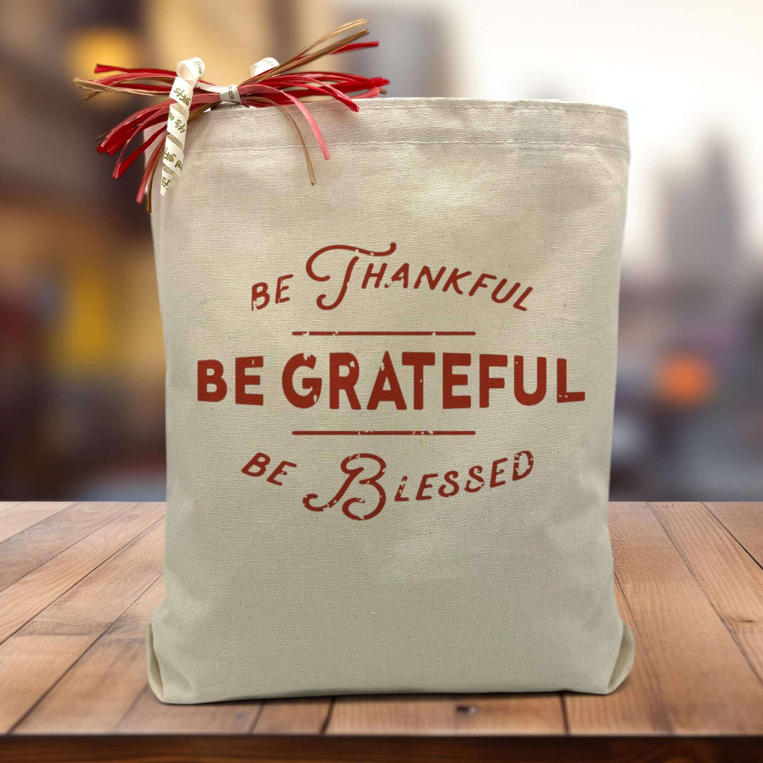 be thankful be grateful be blessed printed on canvas tote bag sitting on table with blurred background