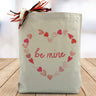 be mine with hearts in a heart shape printed in pink on a canvas tote bag sitting on a table