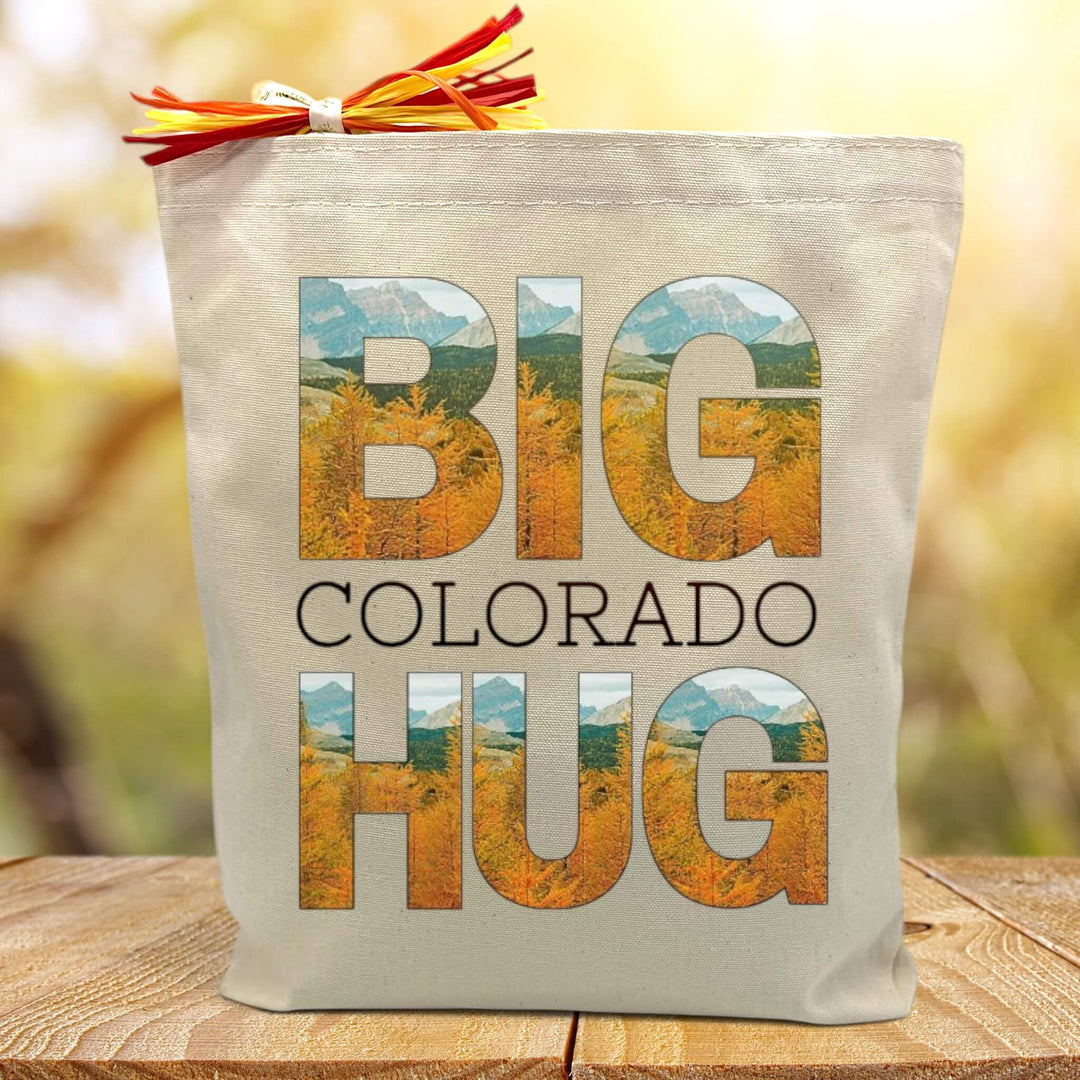 Big colorado hug with an autumn print printed on a canvas tote bag sitting on a wood table