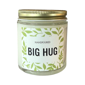 Candle with Big Hug Printed on the front with green leaves around
