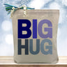 blue big hug printed on a canvas tote bag sitting on a table