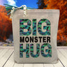 Big Monster hug printed on canvas tote bag sitting on a table with a blurred fall background