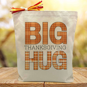 big thanksgiving hug in orange printed on a canvas tote bag sitting on a table with a blurred background