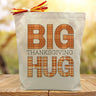 big thanksgiving hug in orange printed on a canvas tote bag sitting on a table with a blurred background