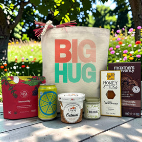 big hug in teal and pink with tea, poppi, oatmeal, candle, honey sticks and cookies sitting on a table