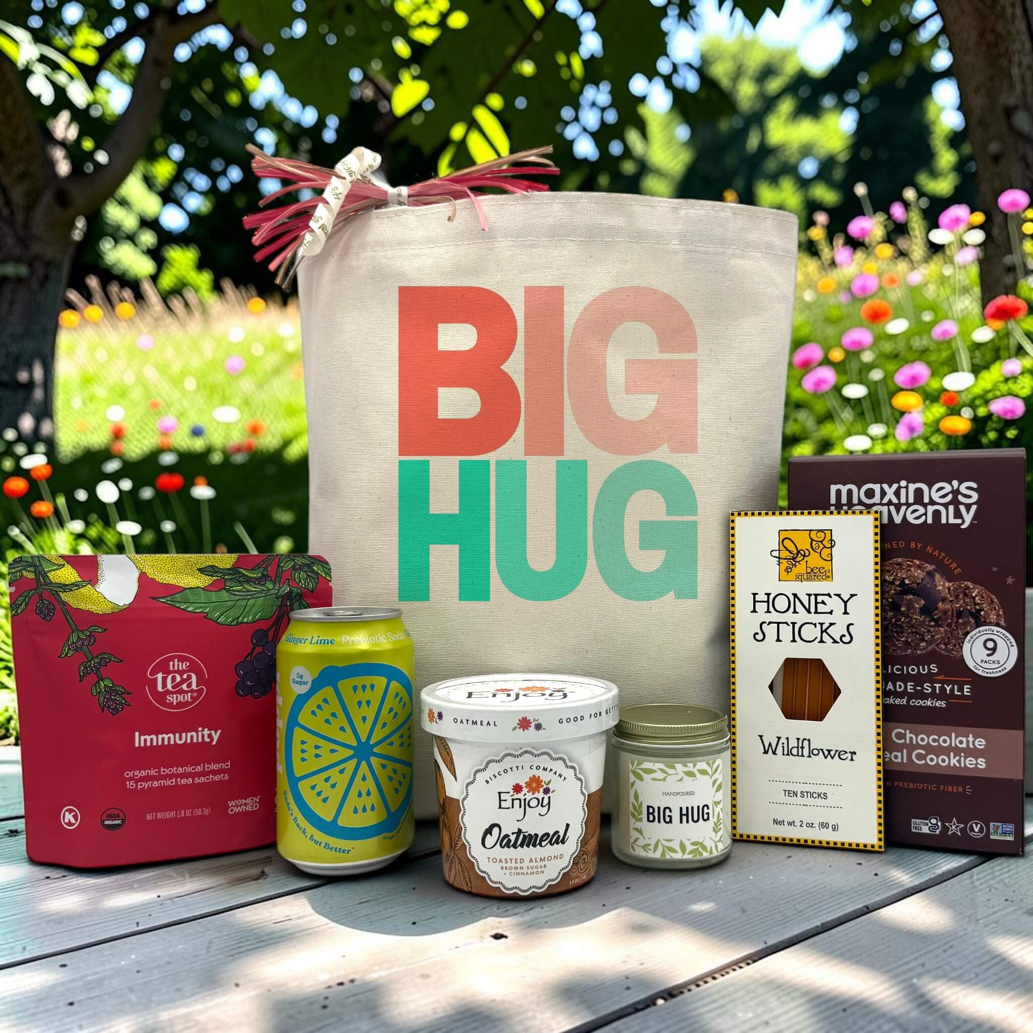 big hug in teal and pink with tea, poppi, oatmeal, candle, honey sticks and cookies sitting on a table