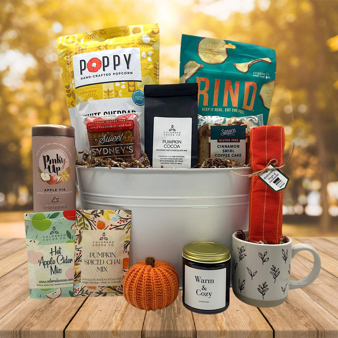 gourmet fall gift basket filled with popcorn, cocoa, sweet treats, tea, candle mug and more sitting on a table