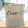 Cheers! in black printed on canvas tote bag sitting on table with white blurred background