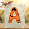Orange letter A with bats, custom letter printed on canvas tote bag sitting on a table