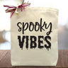 spooky vibes printed on a canvas tote bag sitting on a table