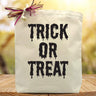 Trick or treat in black printed on a canvas tote bag sitting on a table