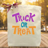 purple blue and orange trick or treat printed on a canvas tote bag sitting on a table