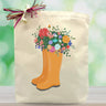 orange rainboots with flowers coming out the top printed on a tote bag sitting on a wooden table