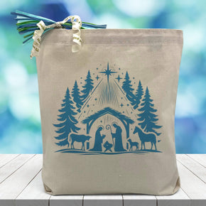 away in a manger in blue printed on a canvas tote bag sitting on a wood table with a blurred blue background