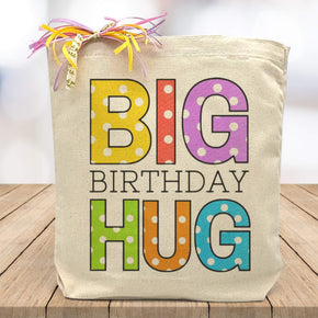 multi color big birthday hug printed on a canvas tote bag sitting on a table with a white blurred background