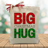 red and green plaid big christmas hug printed on a canvas tote bag sitting on a wood table
