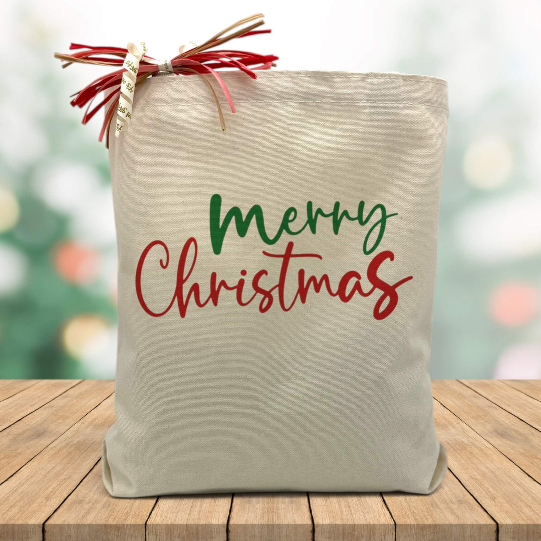 red and green merry christmas printed on a canvas tote bag sitting on a wood table