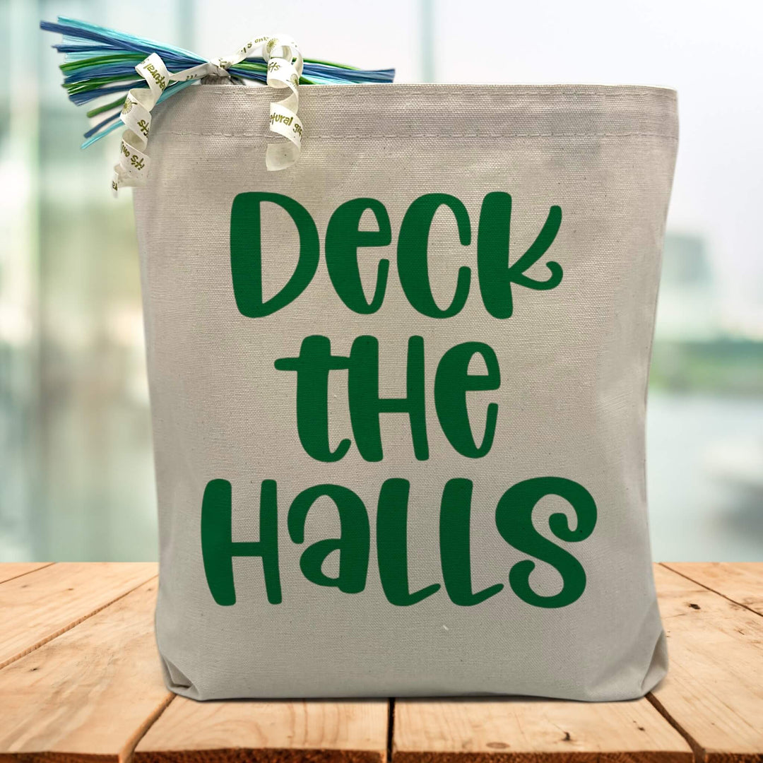 green deck the halls printed on a canvas tote bag sitting on a wood table