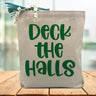 green deck the halls printed on a canvas tote bag sitting on a wood table