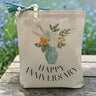 Floral arrangement with happy anniversary printed on a canvas tote bag sitting on a rustic table with a floral background