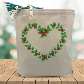 Holiday heart wreath printed on a canvas tote bag sitting on a wood table with a blured holiday background
