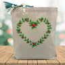 Holiday heart wreath printed on a canvas tote bag sitting on a wood table with a blured holiday background