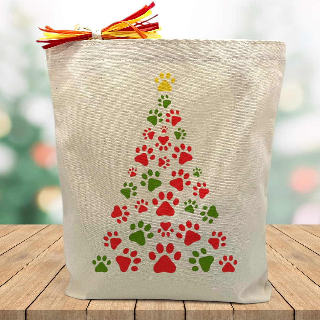 red and green paw print christmas tree printed on a canvas tote bag sitting on a wood table