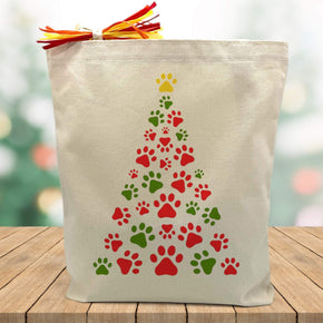 red and green paw print christmas tree printed on a canvas tote bag sitting on a wood table