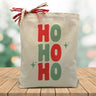 Ho Ho Ho in red and green printed on a canvas tote bag sitting on a wood table