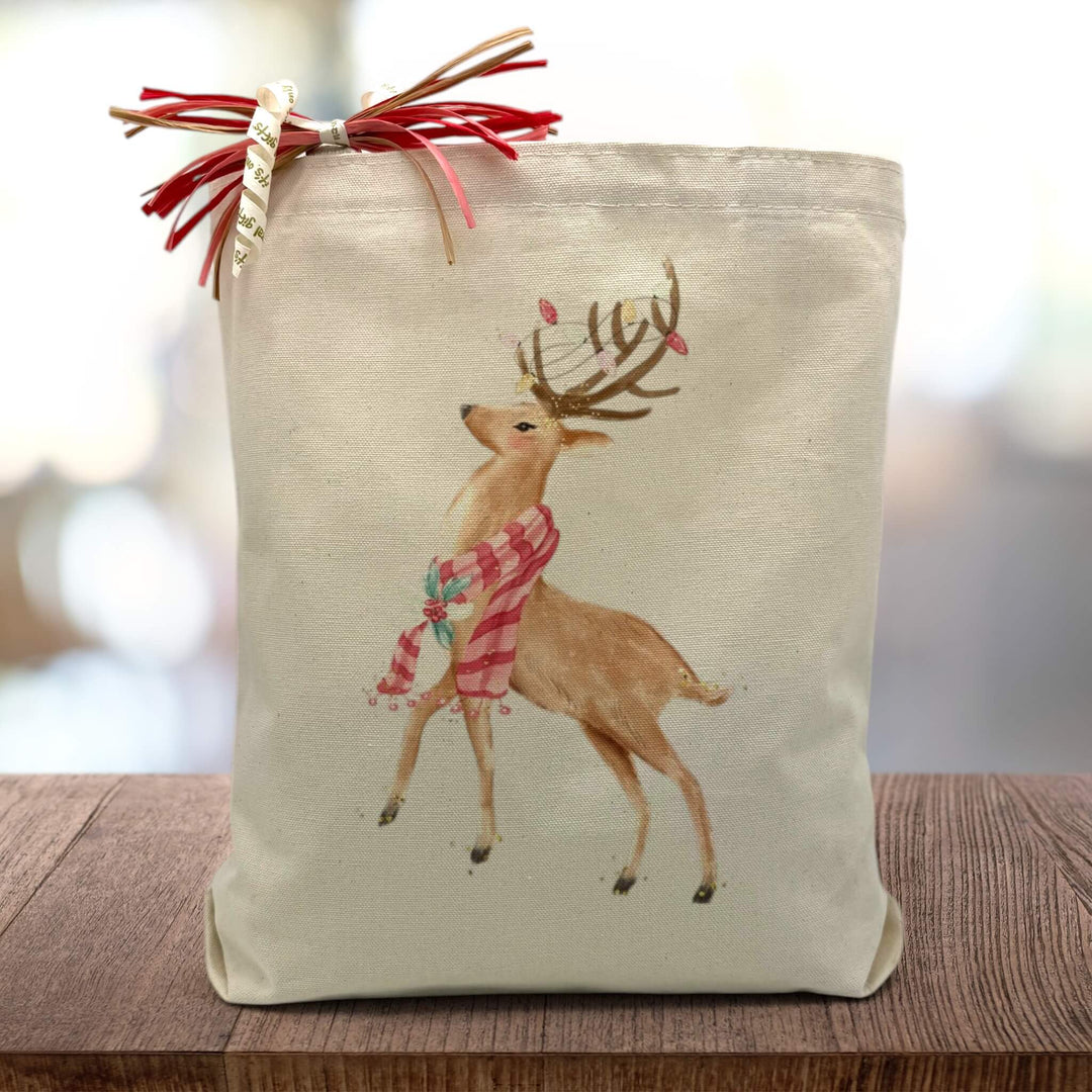 holiday themed reindeer printed on a canvas tote bag sitting on a wood table with a blurred background